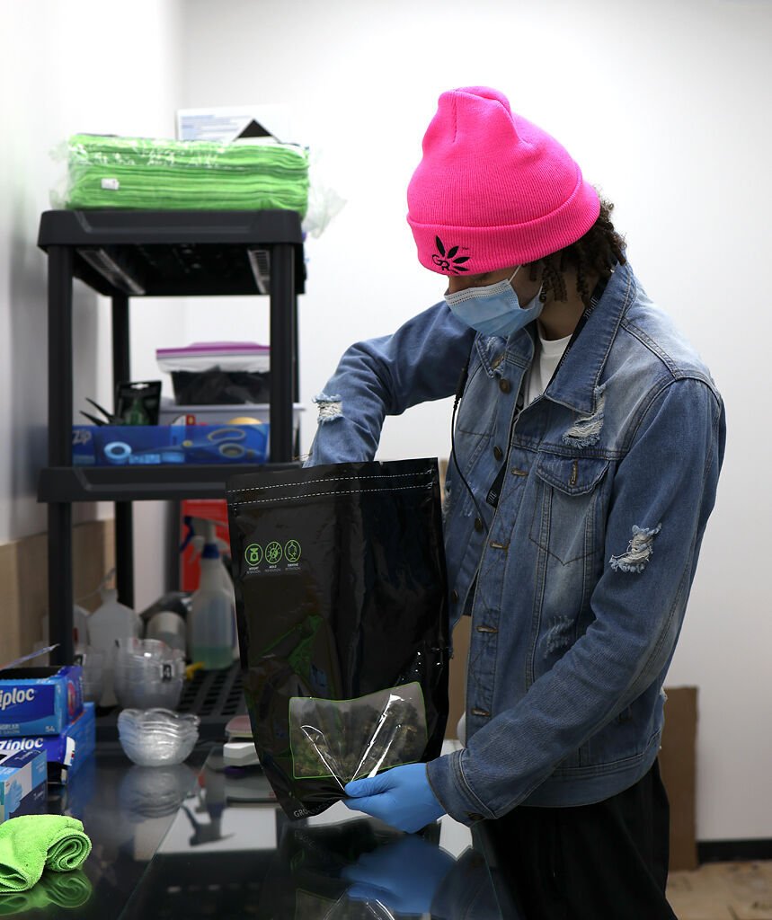 A Green Releaf employee packages 3.5 grams of Bubba Fett marijuana into a bag